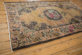 Distressed vintage Oushak rug with fuchsia rose bouquet, Rococo medallion, and abrashed dark beige field.