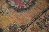 Fuchsia rose bouquet and Rococo outline on distressed dark beige Oushak rug.