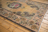 Distressed corner of vintage Oushak rug, showing muted floral border and intact selvage.