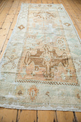 Distressed Oushak runner's worn rams horn medallion, geometric patterns, and soft beige tones.