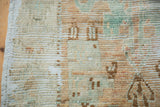 Distressed Oushak rug's worn texture, visible foundation, side selvage, and seafoam tones.