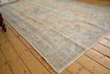 Close-up: Distressed pile, pale apricot field, and dusty blue border on a vintage Oushak.