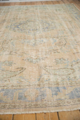 Vintage distressed Oushak carpet showing low pile, foundation, and pale blue vine motifs.