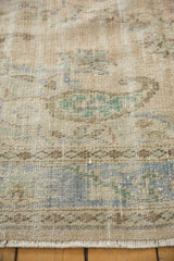 Distressed vintage Oushak carpet pile showing worn texture, faded beige hues, and fringe.