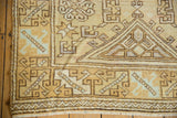 Distressed Oushak corner, geometric hook and latch motifs, worn gold, ivory, and mint.