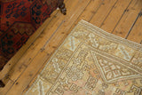 Distressed pile of vintage Oushak rug with geometric hook and latch motifs in gold and rose.
