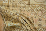 Distressed Oushak rug detail with geometric hook and latch motifs and worn pile.