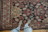 Decorative cloudband border and distressed field of the Oushak rug with rich red and gold.