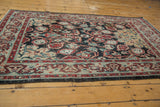 Distressed vintage Oushak rug close-up: worn navy field, red, blue, gold cloudband border details.