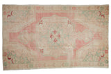 Vintage distressed Oushak rug featuring a rose medallion, seafoam borders, and beige tones.