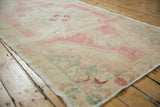 Distressed Oushak rug corner detail, revealing blush, seafoam border and mostly even wear to knot heads.