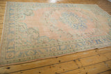 Vintage Distressed Oushak carpet corner with blush, pale apricot, and mint green floral spandrel.