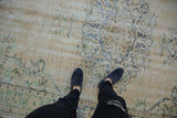 Textured distressed Oushak rug with faded ivory field, pale blue, green scrolled patterns.