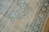 Distressed Oushak rug pile with visible foundation, worn ivory field, faded blue-green scrolled motifs.