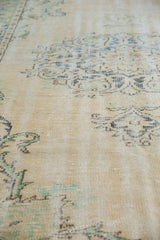 Distressed Oushak rug texture with worn knot heads, visible foundation, faded tendril patterns.