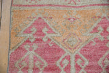 Distressed short pile with geometric raspberry and saffron patterns on inverted ground.