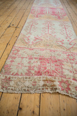 Textured pile and geometric raspberry red plant motifs on the distressed vintage Oushak runner end.