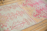 Distressed Oushak runner shows geometric plants on alternating ivory and raspberry grounds.
