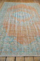 Distressed Oushak carpet pile showing even wear, faint foundation, pale tangerine and muted blue-green.