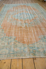 Distressed vintage Oushak rug with worn pile texture in pale tangerine, blue, and green.