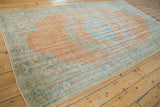 Vintage distressed Oushak rug's secured selvage, displaying worn pale tangerine and seafoam motifs.