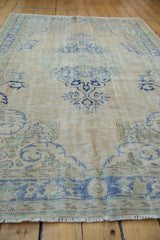 Distressed pile texture with ivory, pale blue border, and fringe on the vintage Oushak rug.
