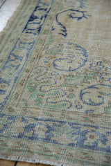 Distressed Oushak carpet's worn pile, visible foundation, pale blue, seafoam green patterns, and fringe.