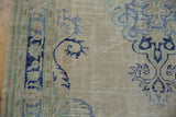 Distressed vintage Oushak rug with visible foundation, ivory field, and blue, green tone-on-tone abrashes.