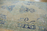 Textured detail of vintage distressed Oushak carpet, with visible knot heads, pale blue, and seafoam green motifs.