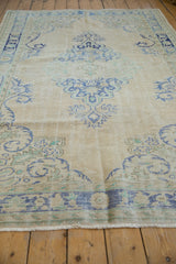 Distressed ivory fringe and geometric border in pale blue, seafoam green on a vintage Oushak carpet.