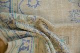 Distressed vintage Oushak rug texture, with abrash in ivory, pale blue, and seafoam green.
