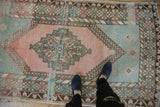 Distressed vintage Oushak rug, faded blush stepped medallion, ocean green corners, geometric borders.