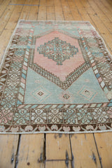 Distressed Vintage Oushak rug detail: stepped medallion, hook and latch motif in blush, mint, and bronze.
