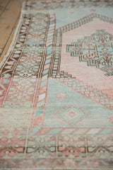 Distressed vintage Oushak rug detail with blush, mint green palmettes, and barber pole border.