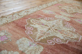 Abrashed Oushak runner detail: intricate scrolled rams horn motif in ivory, blush, and brown.