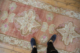 Distressed Turkish Oushak runner detail: scrolled rams horn motif, abrashed field, faded red and ivory.