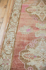 Distressed vintage Oushak runner with abrashed pale raspberry field and intricate scrolled border.