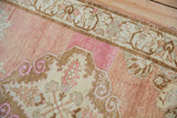 Vintage distressed Oushak rug runner with faded raspberry field, abrash, and scrolled patterns.