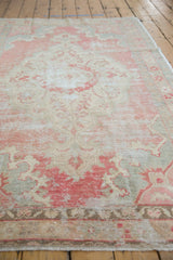 Close-up of vintage distressed Oushak rug pile, highlighting worn pale red tones and visible foundation.