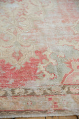 Distressed vintage Oushak rug pile showing blush, ivory, slate, and exposed foundation.