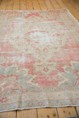 Vintage distressed Oushak rug pile with faded blush and beige floral patterns, showing foundation.