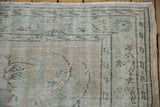 Distressed vintage Oushak rug corner with worn texture, ivory, beige, pale blue patterns.