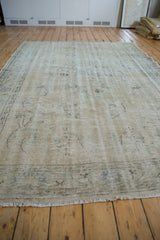Distressed ivory and beige pile with faded floral vinery, showing knot heads.