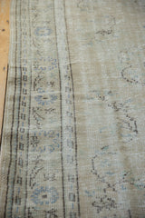 Oushak carpet detail: distressed texture, pale blue patterns on beige, mostly even wear to foundation.