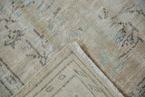 Folded corner of distressed Oushak rug revealing worn pile and hand-knotted foundation.
