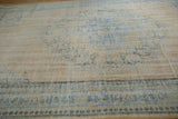 The distressed texture of the vintage Oushak carpet, showing mostly even wear to the knot heads.