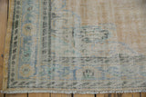 Worn corner of a vintage Oushak carpet with a pale blue and beige border and visible knot heads.