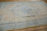Lengthwise view of a distressed Oushak carpet, showing the texture of its mostly even wear and low pile.
