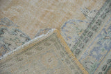 Folded corner of a vintage Oushak rug showing the hand-knotted foundation and restored side cord.