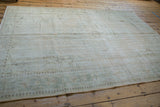 Distressed Oushak rug corner, featuring faded beige, pale seafoam border patterns.